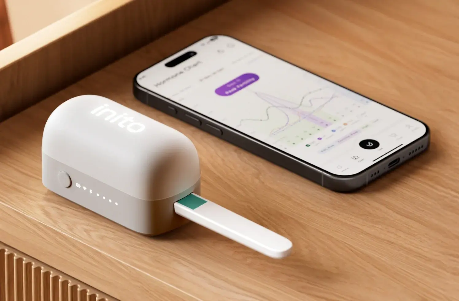 The full Inito system showing the standalone wireless reader with the Fertility Strip inserted and Inito app on its side